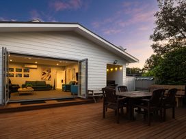 An outdoor deck with seating and a view into a living room at Bayview Haven - Waikawa Retreat in Picton
