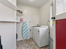 A laundry room with a washing machine and ironing board at Taupo view road holiday home Taupo