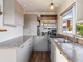 A kitchen with cabinets, countertop, sink, stove, and coffee machine at Taupo view road holiday home in Taupo