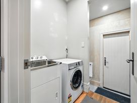 A laundry room with a washing machine and laundry tub at The Alpine Edge - Windwhistle Holiday Home, Canterbury