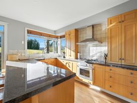 A kitchen with cabinets, sink, stove, and window at The Alpine Edge - Windwhistle Holiday Home in Canterbury