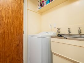 A laundry room with a washing machine and sink at Beachfront Landing - Pauanui Holiday Home
