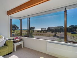 A living room with a view of the outdoor scenery at Beachfront Landing - Pauanui Holiday Home, Pauanui