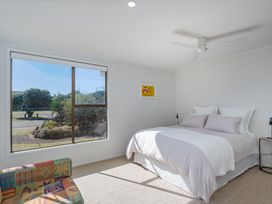 A bedroom with a bed and a window at Beachfront Landing - Pauanui Holiday Home in Pauanui