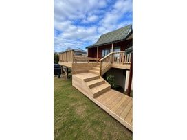 An outdoor deck area with stairs and a house at Beachfront Landing - Pauanui Holiday Home Pauanui