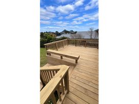 An outdoor deck area with wooden decking and railing at Beachfront Landing - Pauanui