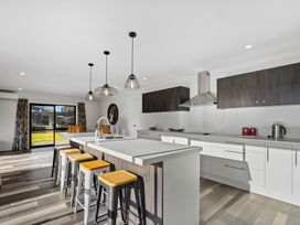 A kitchen with bar stools and modern appliances at Sunrise Hideaway - Cromwell Holiday Home in Cromwell