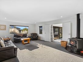 A living room with furniture and a wood stove at Sunrise Hideaway - Cromwell Holiday Home, Cromwell