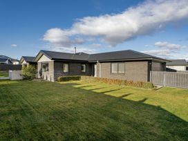 A house with a lawn and fence at Sunrise Hideaway - Cromwell Holiday Home, Cromwell