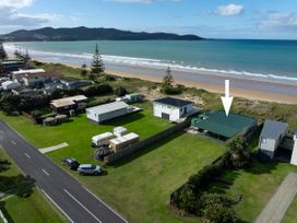 An aerial view of a beachside property with houses and cars at Natives Nest - Karikari Peninsula Escape Kaitaia
