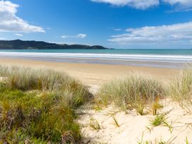 A beach scene with sand, grass and ocean view at Natives Nest - Karikari Peninsula Escape, Kaitaia