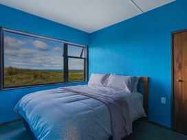 A bedroom with a bed and window at Natives Nest - Karikari Peninsula Escape Kaitaia