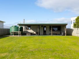 A house with a water tank and outdoor seating at Natives Nest - Karikari Peninsula Escape Kaitaia