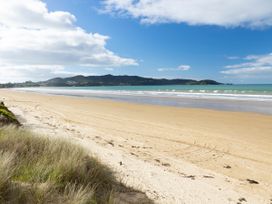 A beach with sand and ocean waves at Natives Nest - Karikari Peninsula Escape Kaitaia