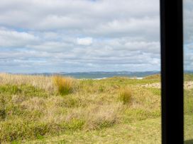A view of grass and hills under a cloudy sky at Natives Nest - Karikari Peninsula Escape Kaitaia
