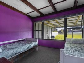 A bedroom with two beds and a window overlooking the yard at Natives Nest - Karikari Peninsula Escape Kaitaia