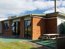 A patio area with a table and bench at Natives Nest - Karikari Peninsula Escape in Kaitaia
