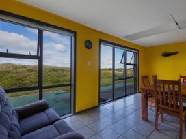 A living room with a dining area and windows at Natives Nest - Karikari Peninsula Escape Kaitaia