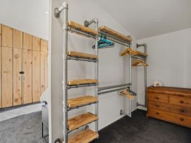 A clothing rack with wooden shelves and dresser in a bedroom at Eight on Jackson - Luggate Holiday Home