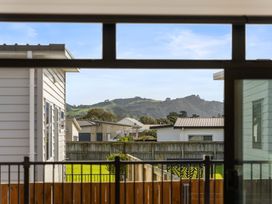 A view of houses and mountains from a window at Waihi Beach Holiday Home in Waihi Beach