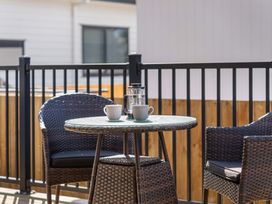 A table with coffee cups and a coffee press on a balcony at Waihi Beach Holiday Home Waihi Beach