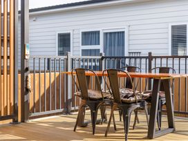 An outdoor seating area with a table and chairs at Waihi Beach Holiday Home in Waihi Beach