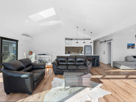 A living room with sofas and a kitchen island at Waihi Beach Holiday Home in Waihi Beach