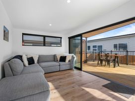 A living room with a sofa and a sliding door leading to a deck at Waihi Beach Holiday Home in Waihi Beach