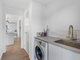 A laundry room with washing machine and sink at Waihi Beach Holiday Home in Waihi Beach