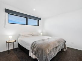 A bedroom with a bed and bedside lamp at Waihi Beach Holiday Home in Waihi Beach
