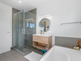 A bathroom with a shower and bathtub at Waihi Beach Holiday Home in Waihi Beach