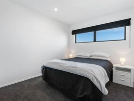 A bedroom with a bed and nightstand at Waihi Beach Holiday Home in Waihi Beach