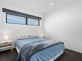 A bedroom with a bed and nightstand at Waihi Beach Holiday Home Waihi Beach