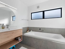 A bathroom with a bathtub and sink at Waihi Beach Holiday Home in Waihi Beach