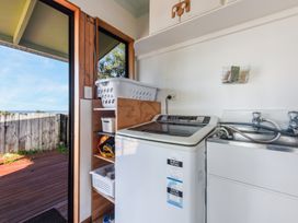 A laundry room with a washing machine and laundry basket at Quail Rise - Collingwood Holiday Home in Collingwood