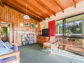 A living room with a sofa, bookshelf, and television at Quail Rise - Collingwood Holiday Home, Collingwood