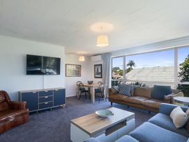 A living room with a television and dining area at The Beach Base - Paraparaumu Holiday home in Paraparaumu
