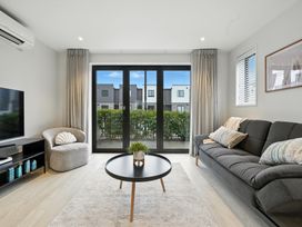 A living room with a sofa, armchair, coffee table and television at Townheart on Hereford - Christchurch City Apartment