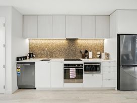 A kitchen with cabinets, sink, stove, and refrigerator at Townheart on Hereford - Christchurch City Apartment