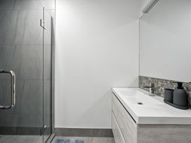 A modern bathroom with a shower and sink at Townheart on Hereford - Christchurch City Apartment