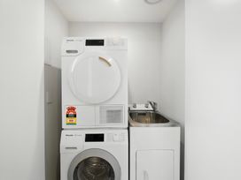 A laundry room with a washer and dryer stacked in Townheart on Hereford - Christchurch Holiday Home Christchurch