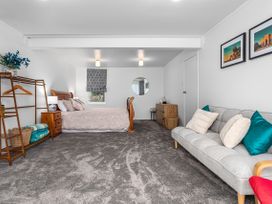A bedroom with a bed and sofa at Ohope in Ohope