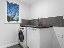A laundry room with a washing machine and sink at Ohope
