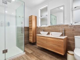 A bathroom with a shower, vanity unit, and toilet at Ohope