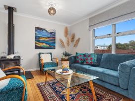 A living room with a sofa, armchair and coffee table at Ohope, Ohope