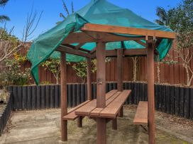 A wooden table and benches with a canopy in an outdoor seating area at Ohope