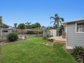 A garden with grass, decking, and a clothesline at Ohope in Ohope