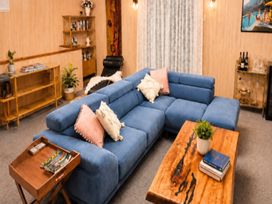A living room with a blue sofa and wooden table at Coastal Haven Retreat - 4 Bedrooms Ohope Beach