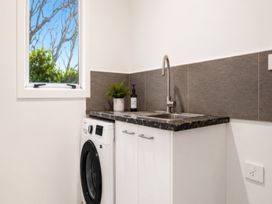 A laundry room with a washing machine and sink at Coastal Haven Retreat - 4 Bedrooms Ohope Beach