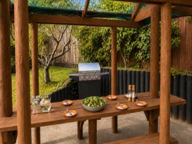 An outdoor dining area with a wooden table and grill at Coastal Haven Retreat - 4 Bedrooms Ohope Beach